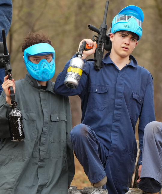 Deux joueurs de paintball en combinaisons et masques de protection bleus discutant de leur stratégie de jeu lors d'une fête d'anniversaire paintball à Rixensart